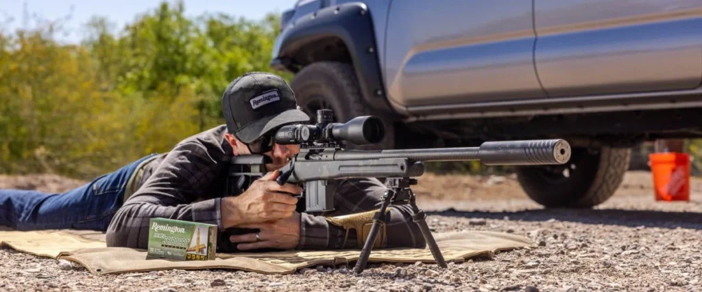 A person laying on the ground shooting in the prone position.
