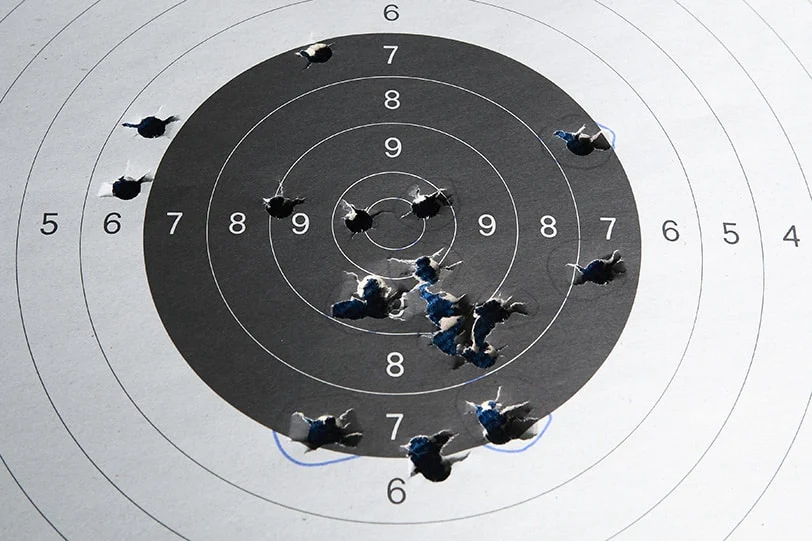 A target with bullet holes all around it.